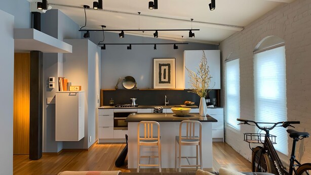 A modern kitchen with a central island, bar stools, and a bicycle.