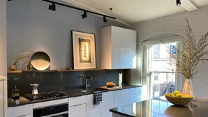 A modern kitchen with white cabinets, a black countertop, and stainless steel appliances.