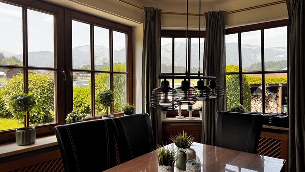A dining area with a table, chairs, and potted plants.
