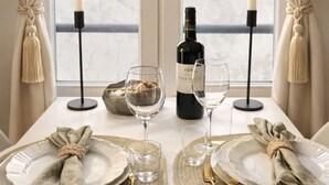 A dining table set with plates, glasses, a wine bottle, and candles, with a view of a building through a window. - 1579 StDominique3 (Paris)