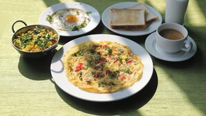 Un desayuno con tortilla, tostadas, café y un acompañamiento en una mesa.