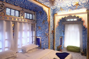 A room with a bed, a window with curtains, and a wall with a blue pattern.