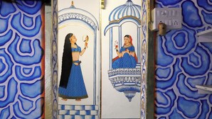 Una puerta con arte mural tradicional indio que representa a dos mujeres vestidas de azul.