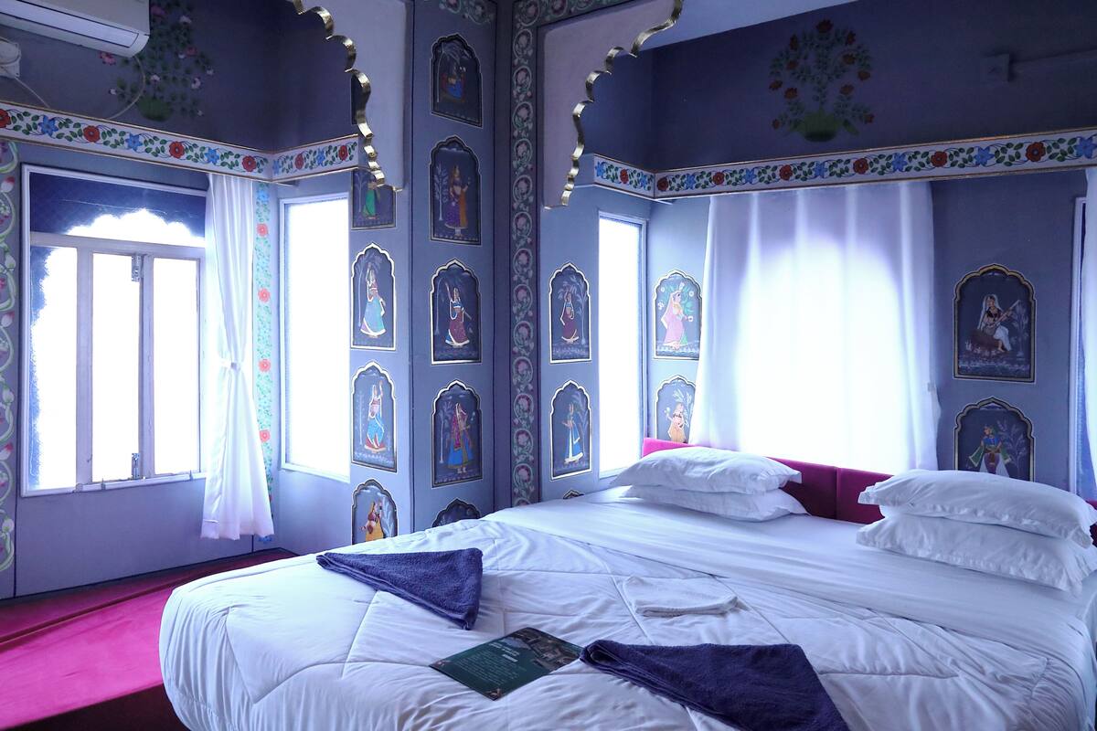 Una habitación con cama, una ventana con cortinas y adornos en la pared.