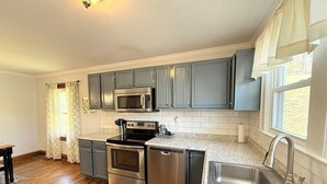 Una cocina moderna con gabinetes grises, electrodomésticos de acero inoxidable y encimera de granito.