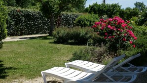 Two white plastic lounge chairs on a gravel path in a garden with green grass and pink flowers. - GITE MURIER WITH POOL AND RIVER (Berrias-et-Casteljau)