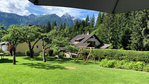 Un giardino curato con altalena, una casa gialla e montagne sullo sfondo.