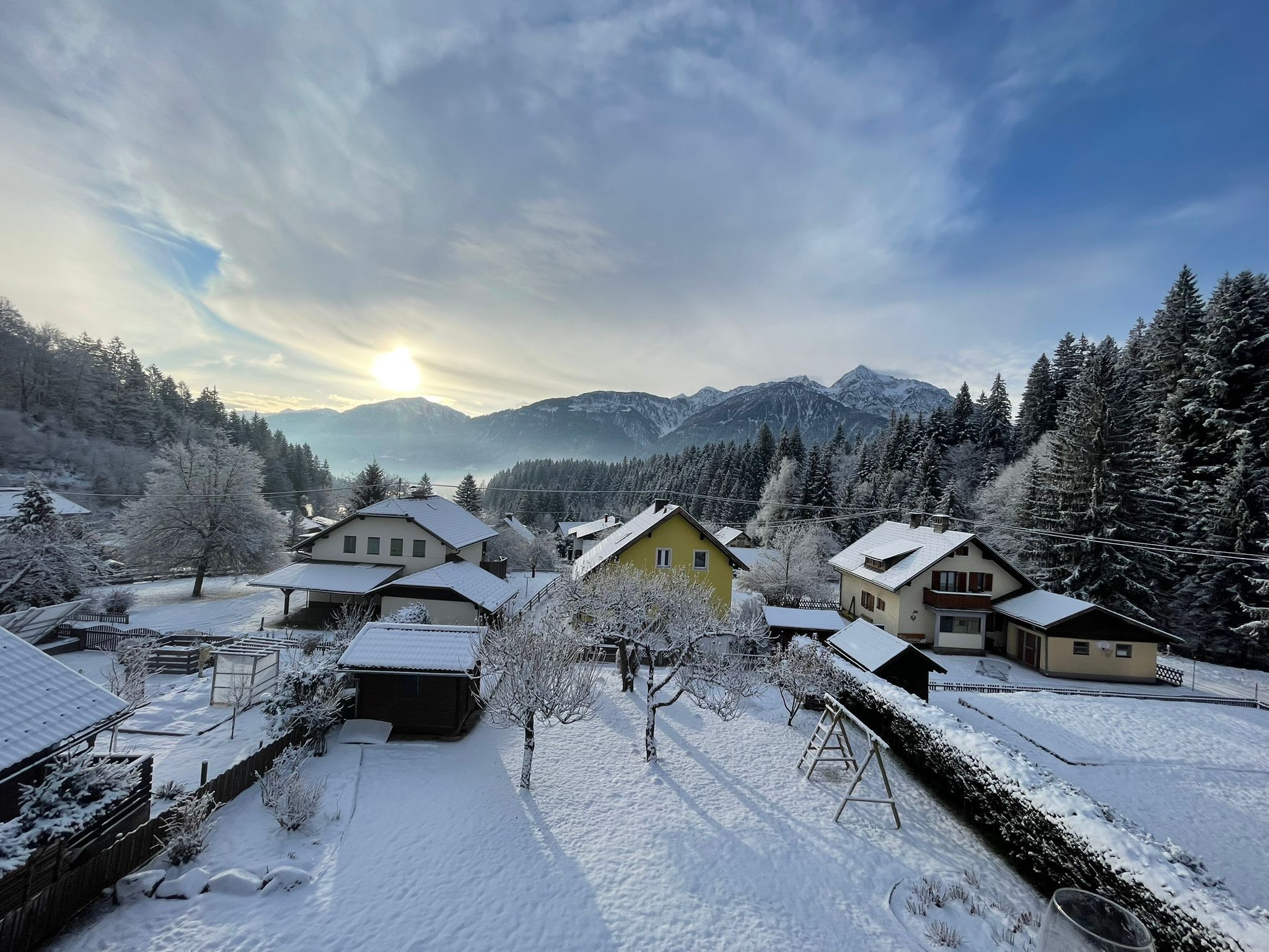 A snow-covered village with houses and mountains in the background.