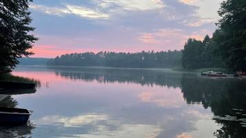 Un lac paisible où flottent des bateaux, entouré d’arbres et sous un ciel dégagé.