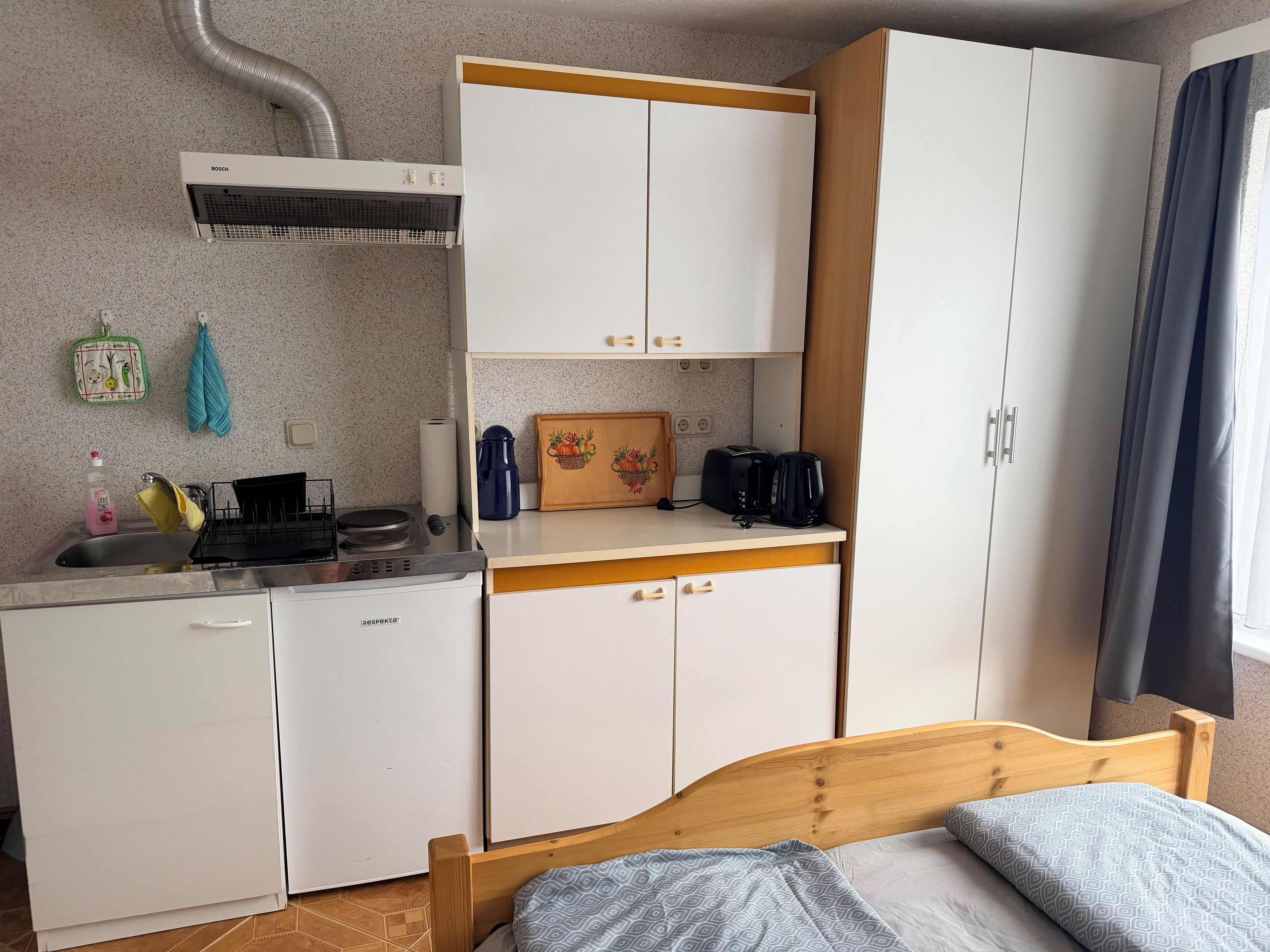 Eine kompakte Küchenzeile mit Klimaanlage von Bosch, einem Spülbecken, einer Kaffeemaschine und einem Toaster.