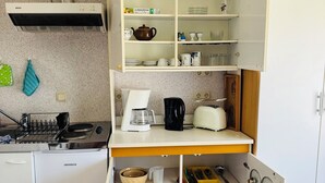 Une petite cuisine équipée d’une friteuse à air Bosch, d’une machine à café et d’une cuisinière.
