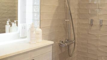 Een badkamer met een douche, wastafel en spiegel.