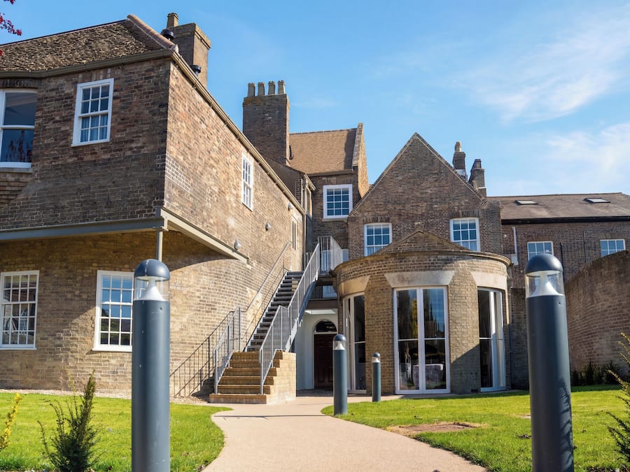 A brick building with a central staircase, a curved glass entrance, and a clear sky.