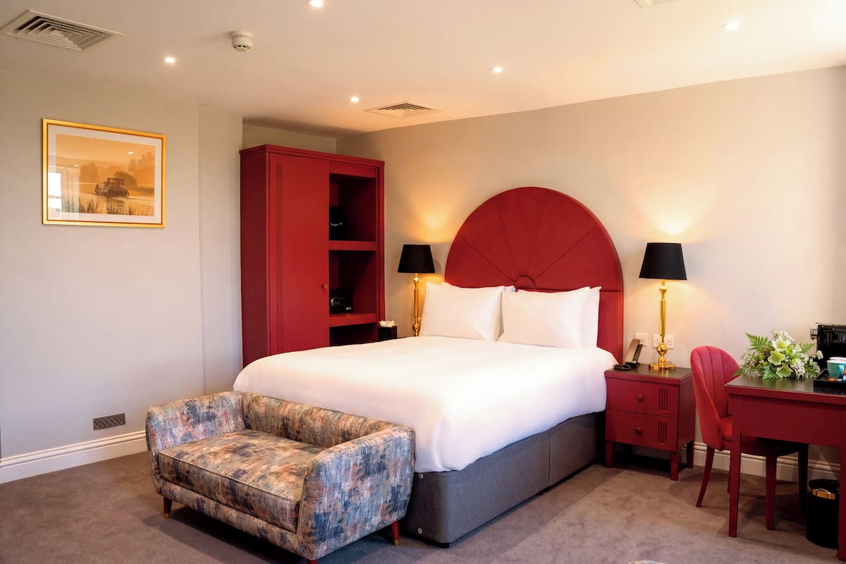 A bedroom with a bed, a red wardrobe, a chair, a desk, and a lamp.