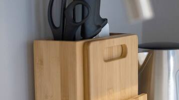 A wooden kitchen utensil block with a knife and scissors on top, a stainless steel pot, and a white countertop.