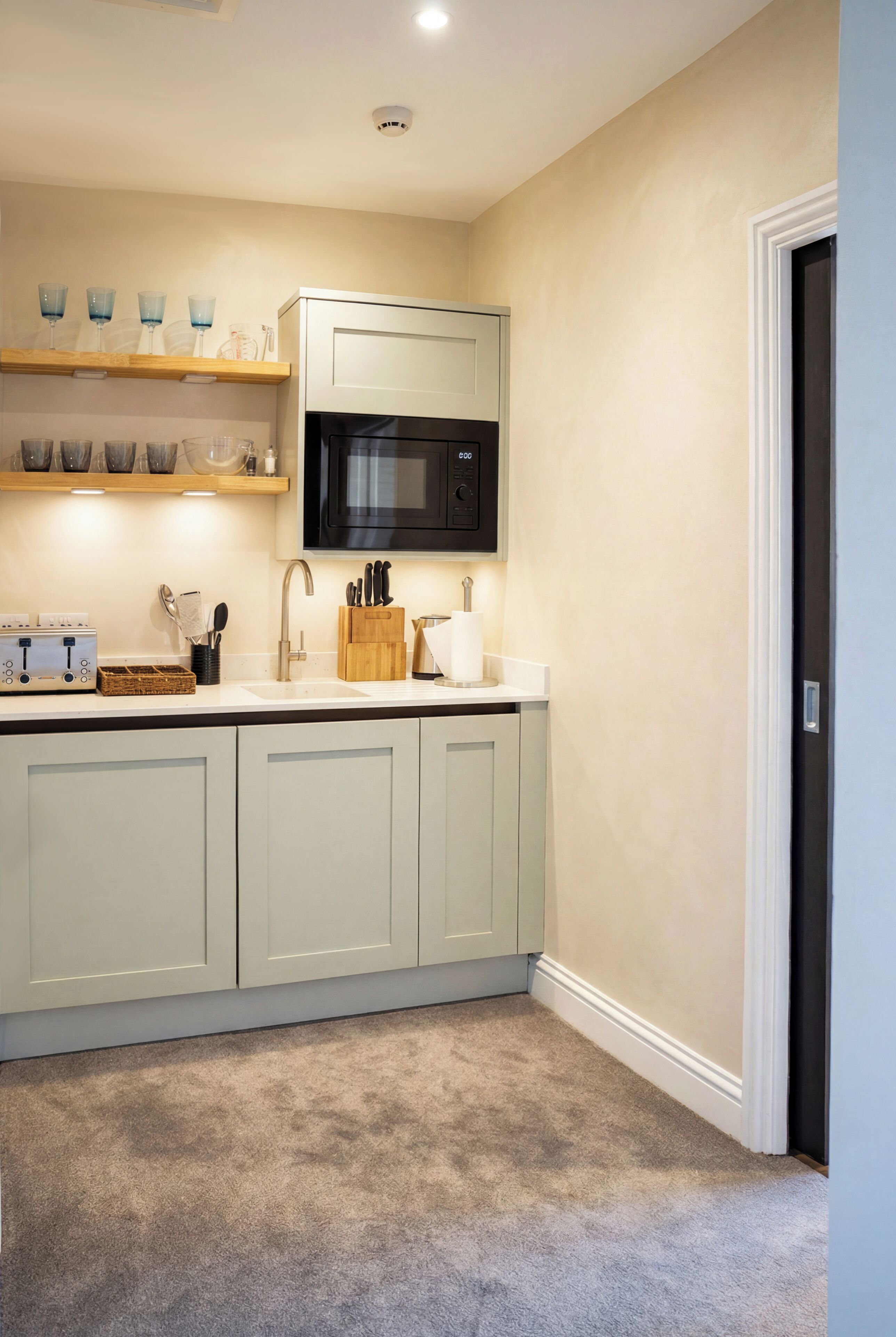 A kitchen with a microwave, toaster, and various utensils.