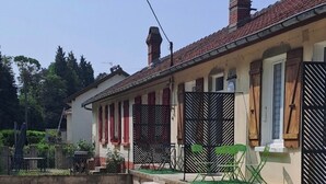 Un edificio de dos plantas con tejado de tejas, camino de grava y portón metálico.