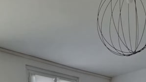 Una sala de estar con un sofá, una mesa de centro, una ventana con persianas y un cuadro colgado en la pared.