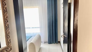 Une chambre d’hôtel avec un lit, une grande fenêtre avec des rideaux légers et une vue sur l’extérieur.