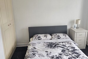 Un dormitorio con cama, mesita de noche y armario.