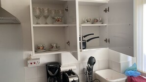 Cuina amb armaris blancs, cafetera, torradora i rentaplat.