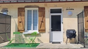 A building with a white door, a window with shutters, and a small outdoor seating area with a table and chairs. - "Mb5" Comfortable stage-T2 whole+Private parking lot  (Damparis)