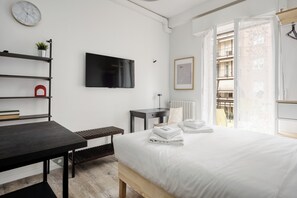 A modern hotel room with a bed, a desk, a TV, a window with a view of a balcony, and a small plant on a shelf. - Stylish Studios near Subway (Milan)