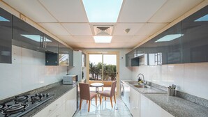 Una cocina moderna con una isla central, un comedor con sillas y vistas a través de un ventanal.