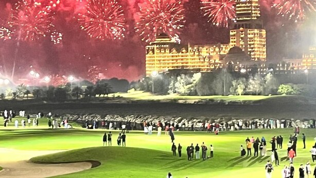Un campo de golf con espectadores y un edificio al fondo.