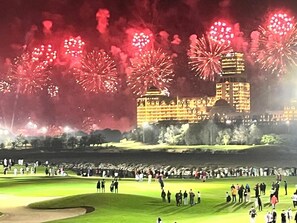 A golf course with spectators and a building in the background.