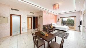 Una habitación de hotel moderna con comedor, sofá, cama y balcón con vistas.