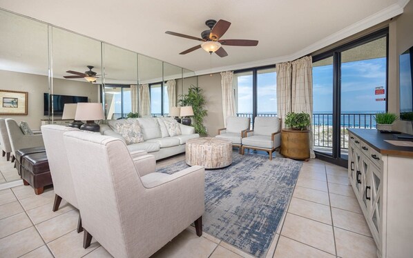 A spacious living room with a sofa, chairs, a coffee table, and a balcony with a view of the beach. - Phoenix X 303 3 Bedroom Condo (Orange Beach)