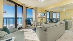 Une chambre d’hôtel avec balcon, un canapé, une télévision et vue sur l’océan.