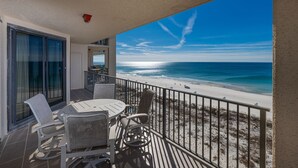 Un balcon donnant sur la plage, une table avec des chaises et une rambarde.