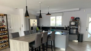 Eine moderne Küche mit einer zentralen Kochinsel, Essbereich und Weinkühlschrank.