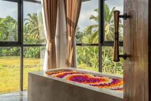 A bathtub with a floral arrangement, large windows, and curtains. - Casa Maddu (Sebatu)