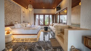 A spacious room with a large bed, a sofa, and a stone wall. - Casa Maddu (Sebatu)