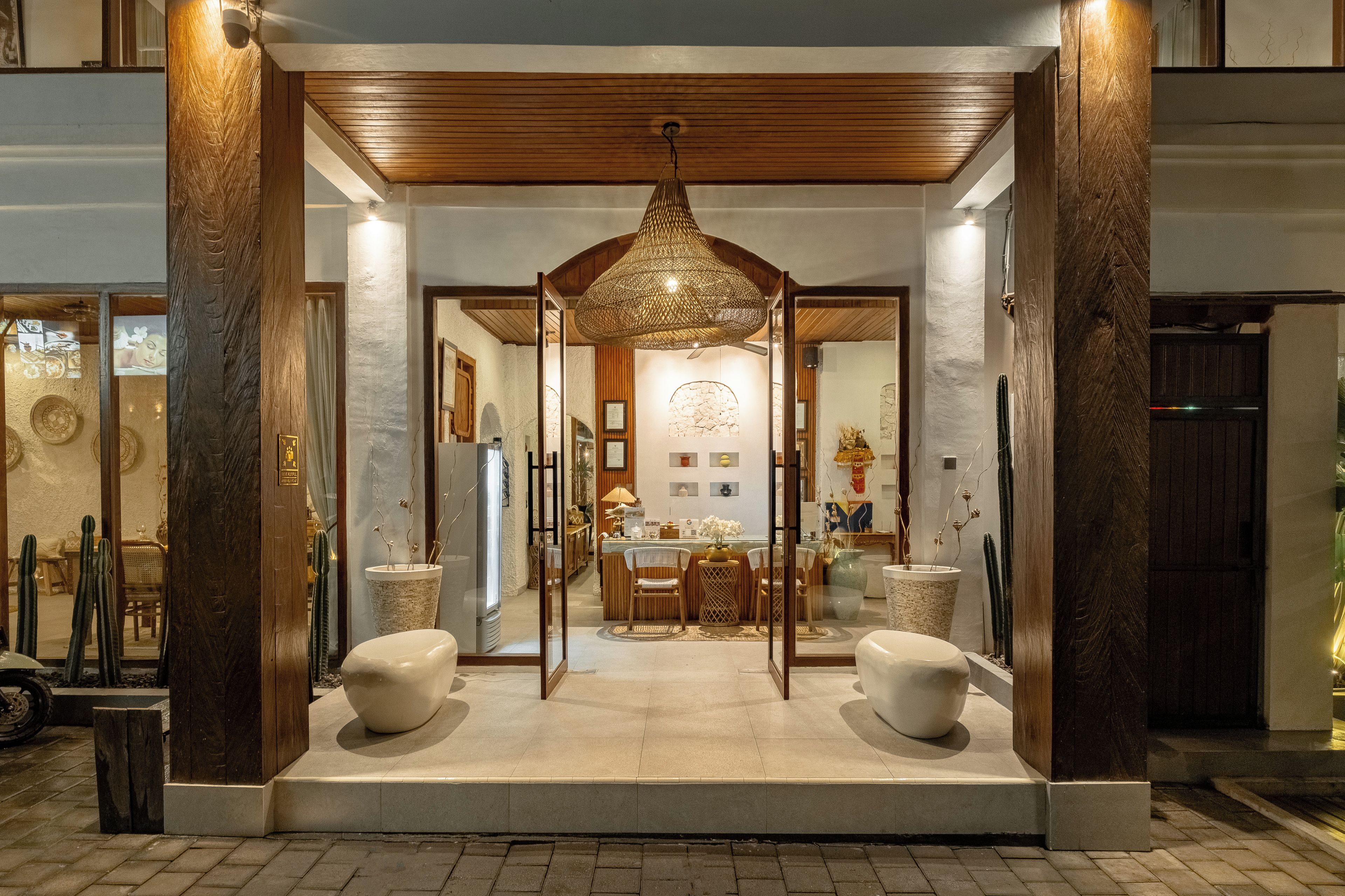 A hotel entrance with a wooden canopy, a reception desk, and a seating area with chairs and tables.