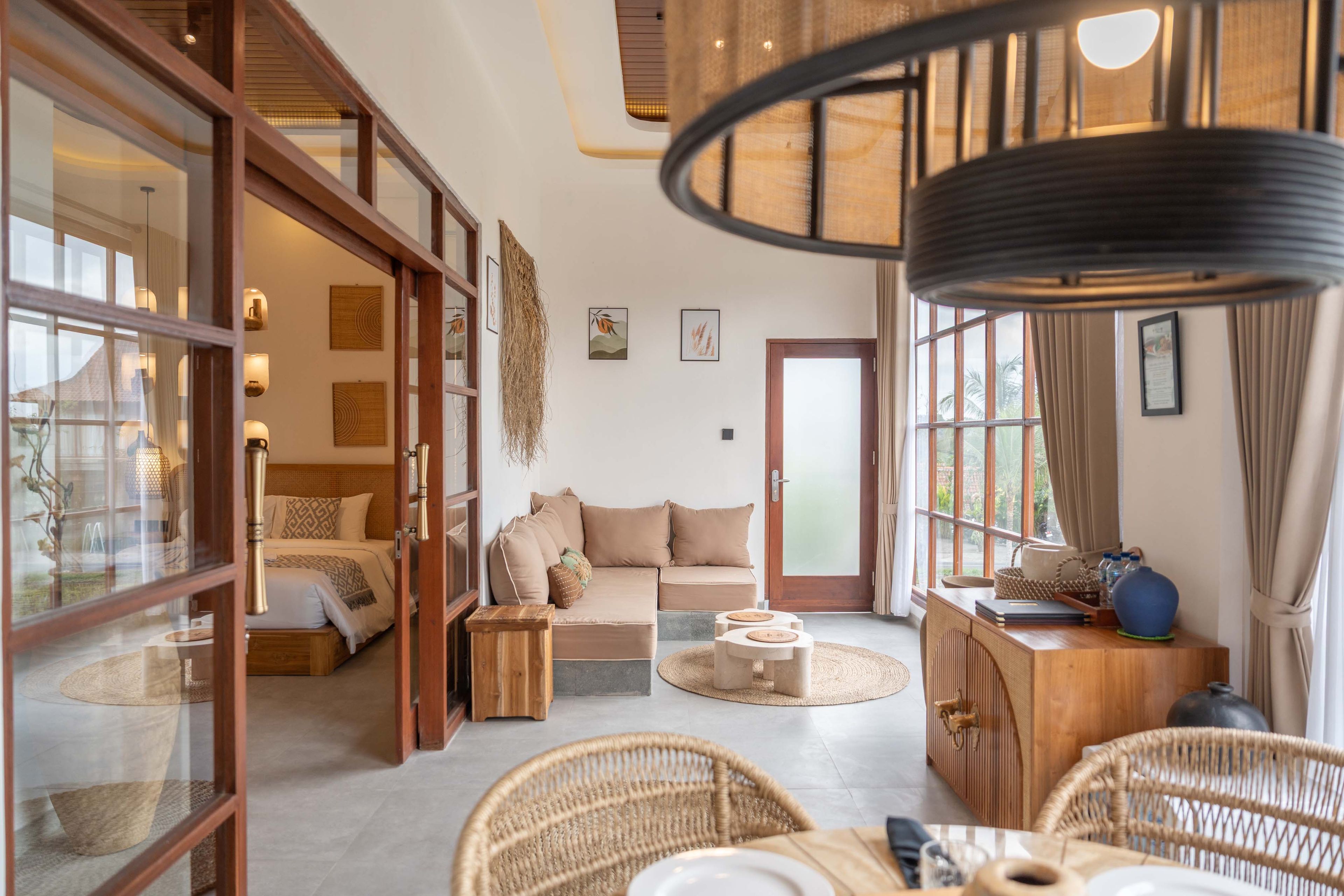 Ein geräumiger Raum mit Bett, Sofa und Essbereich, ausgestattet mit großen Fenstern und einer Deckenleuchte.