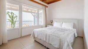 Ein Schlafzimmer mit großem Fenster, einem Bett und einem Nachttisch.
