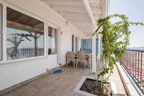 A covered outdoor area with a dining table and chairs, a small plant, and a view of the sea through large windows. - Marmara Yali Evi - Direct Beachfront 3-Room-Apartment (Balikesir)