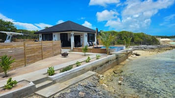 A beachfront property with a covered patio, a swimming pool, and a wooden deck.