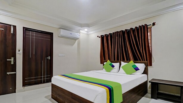 A hotel room with a large bed, a wooden wardrobe, a small bedside table, and a ceiling-mounted air conditioner. - Xotel Koramangala (Bengaluru)