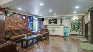 A hotel lobby with a reception desk, a clock, a wall clock, a sofa, armchairs, and a coffee table. - Xotel Koramangala (Bengaluru)
