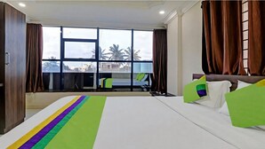 A hotel room with a large bed, a view of palm trees, and a balcony. - Xotel Koramangala (Bengaluru)