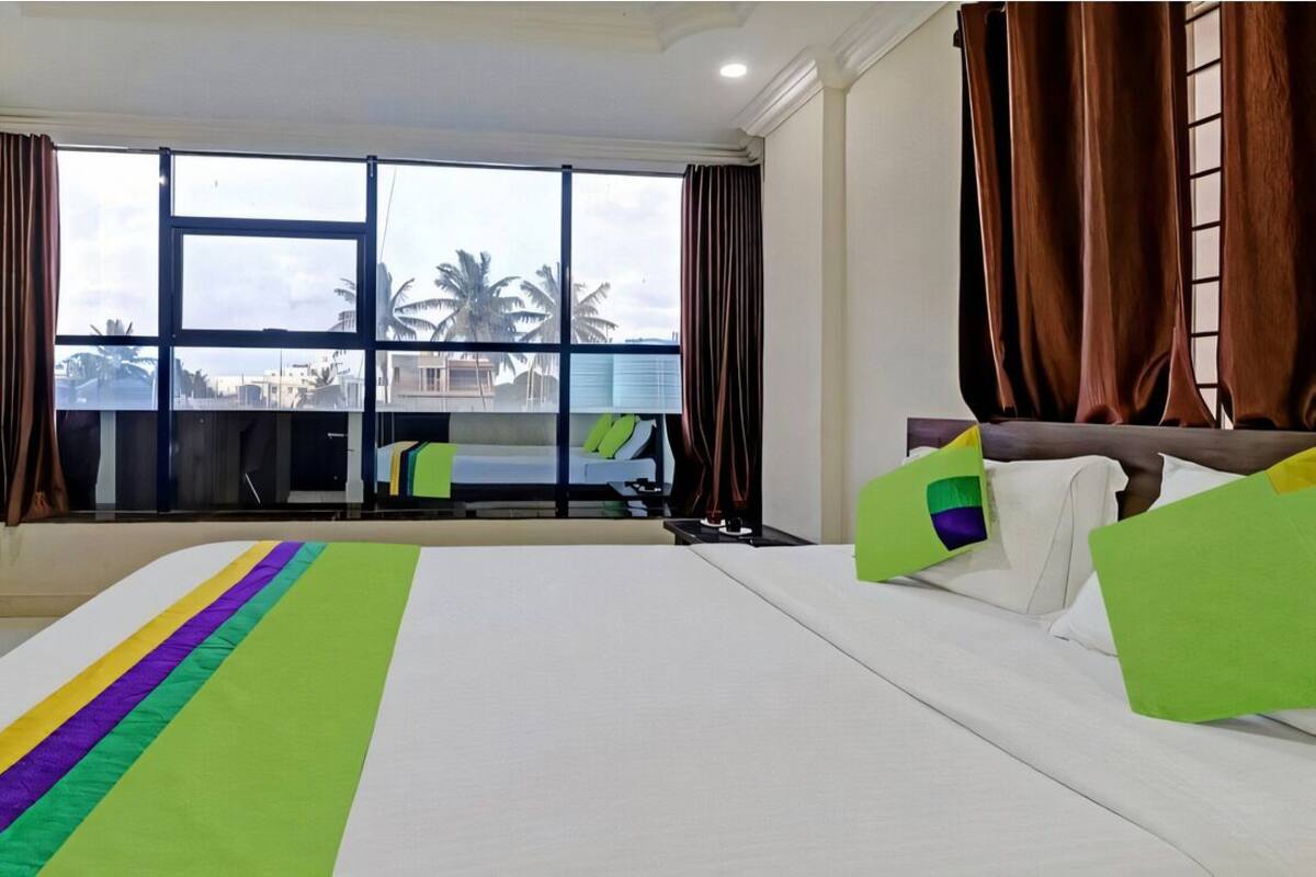 Een hotelkamer met een groot bed, uitzicht op palmbomen en een balkon.