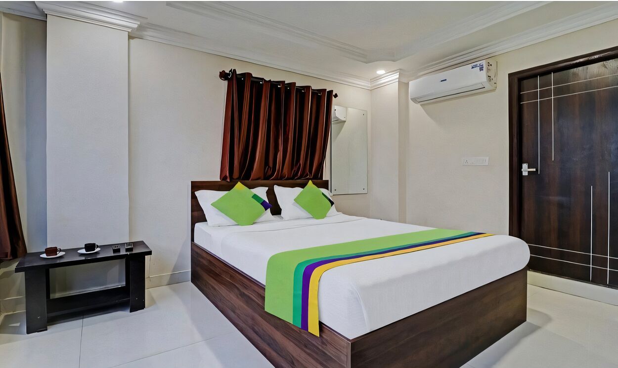 A neatly arranged bedroom with a bed, a bedside table, and a dark wooden door.