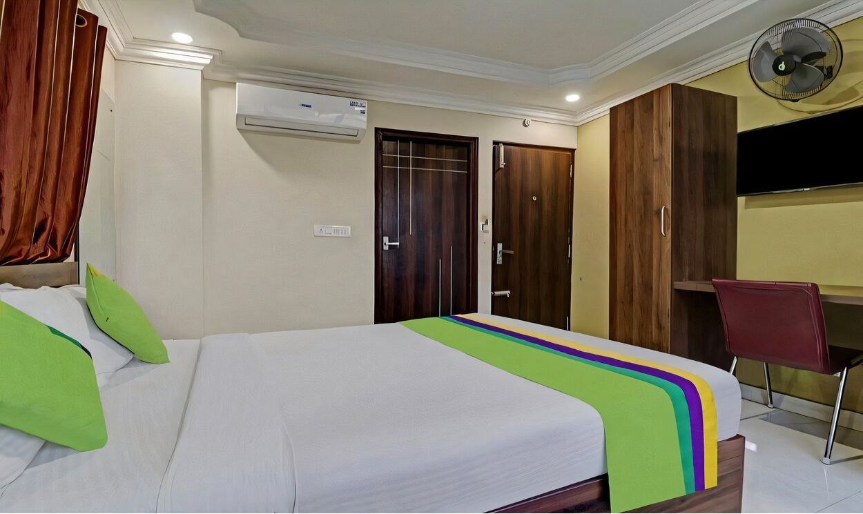 Una habitación de hotel con cama, escritorio, silla y televisor.