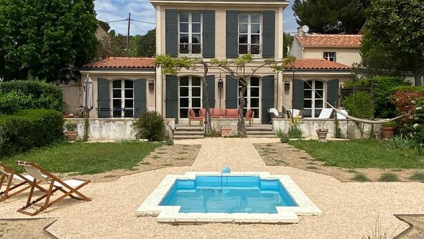 A two-story house with a swimming pool in the front.