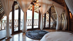 Una habitación con una cama grande, suelo de madera y un techo alto y curvado.